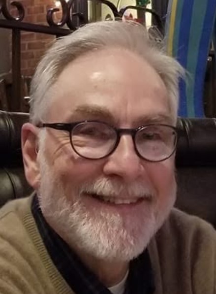 Larry Watson, Skoog, in a tan sweater and glasses